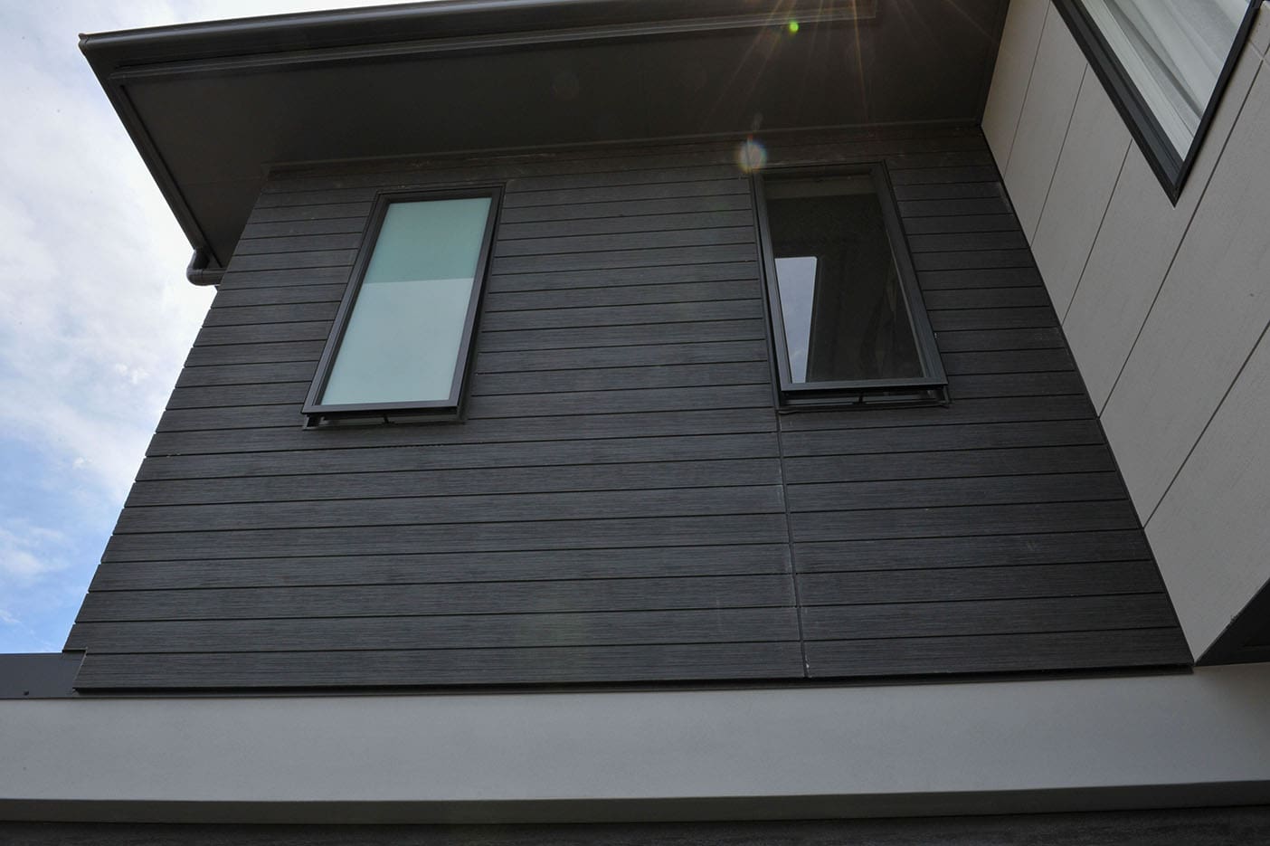Home showcasing INNOVA Montage® cladding in Woodgrain, Black Oak, Concrete Smooth and Stackstone Lime finishes, blending modern textures with durable fibre-cement design.